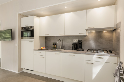 Cucina moderna presso Holiday Park «Kijkduin 9» nei Paesi Bassi con mobili bianchi e fornelli a gas.