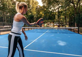 Eine Frau spielt Padel auf einem blauen Außenplatz im Holiday Park Kijkduin 9 in den Niederlanden.