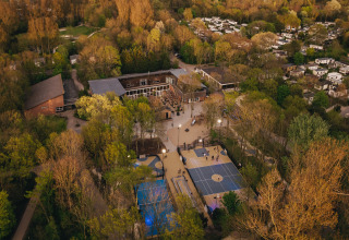 Vista aerea di un lodge tra gli alberi, con campi sportivi e piccoli edifici vicini al tramonto.