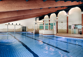 Piscina coperta con soffitto in legno inclinato e servizi moderni in un lodge, perfetta per rilassarsi.