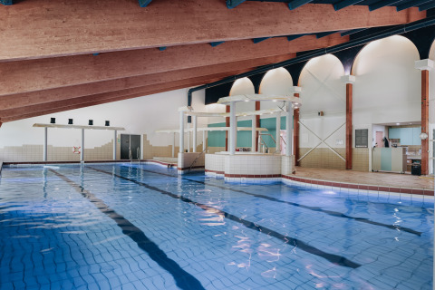 Indendørs swimmingpool med skråt træloft og moderne faciliteter på en lodge, ideel til afslapning.
