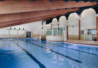 Piscina cubierta con techo de madera inclinado y comodidades modernas en un lodge, ideal para relajarse.