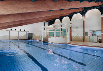 Indoor swimming pool with slanted wooden ceiling and modern amenities at a lodge, perfect for relaxation.