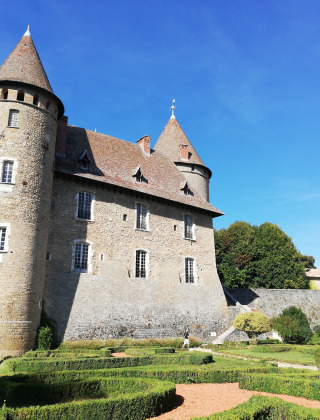 Castillo histórico con torres redondas y jardín cerca de Les Abrets, Auvergne-Rhône-Alpes, Francia, bajo cielo azul.
