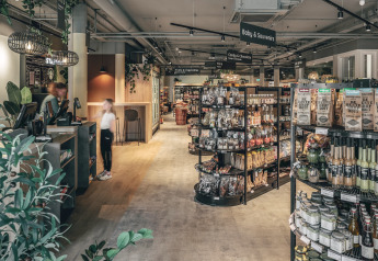 Innenansicht eines modernen Lodge-Shops mit Regalen, Lebensmitteln und Kassenbereich.