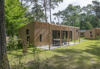 Moderne Holzlodge im Forest Park 't Wolfsven 16 mit Terrasse und Sitzbereich, umgeben von Wald.