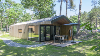 Modernes Holzchalet im Grünen bei Forest Park 't Wolfsven 15 mit Terrasse und Sitzbereich im Freien.