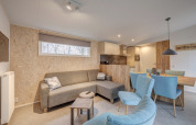 Contemporary living and dining area at Holiday Park «Kijkduin 1», Netherlands, with sofa and blue chairs.