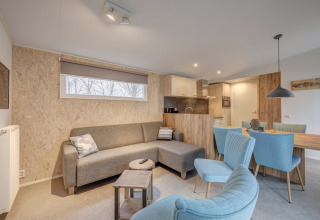 Contemporary living and dining area at Holiday Park «Kijkduin 1», Netherlands, with sofa and blue chairs.
