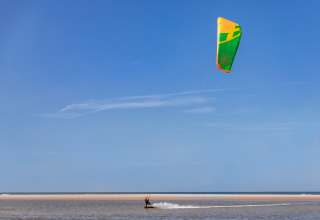 Un kitesurfer sorvola l’acqua vicino all’Holiday Park «Kijkduin 9» nei Paesi Bassi con cielo sereno.