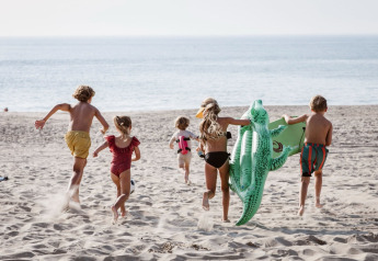 Children running on the sandy beach at Holiday Park “Kijkduin 9” in the Netherlands with an inflatable crocodile.