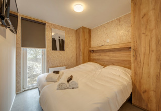 Camera moderna al Holiday Park «Kijkduin 1» con pannelli in legno e letto matrimoniale nei Paesi Bassi.