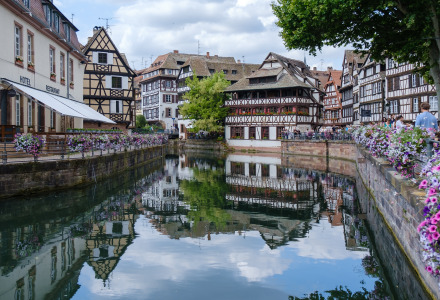 Canal pintoresco rodeado de casas con entramado de madera y flores en el centro histórico de una ciudad francesa.