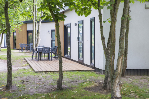 Terrazza all'aperto con tavoli e sedie al lodge Holiday Park Kijkduin 1, circondata da alberi nei Paesi Bassi.