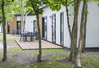 Terrazza all'aperto con tavoli e sedie al lodge Holiday Park Kijkduin 1, circondata da alberi nei Paesi Bassi.