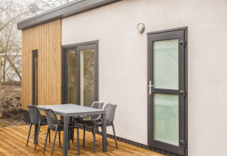 Udendørs terrasse ved Holiday Park «Kijkduin 1» i Holland med bord, stole og moderne facade.