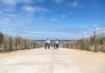 Eine Familie schiebt Fahrräder auf einem Weg zum Strand im Holiday Park 'Kijkduin 9' in den Niederlanden.