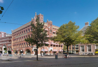 Un impresionante hotel en un edificio histórico de ladrillo, situado en una concurrida esquina con árboles y bicicletas.