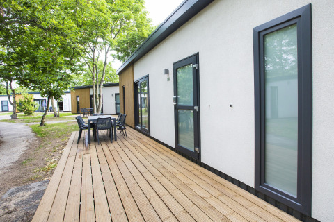 Udendørs terrasse med spisebord ved feriebolig i Holiday Park Kijkduin 1, Holland, omgivet af træer.