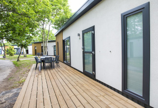 Terraza exterior con mesa de comedor en una cabaña moderna en Holiday Park Kijkduin 1, Países Bajos.