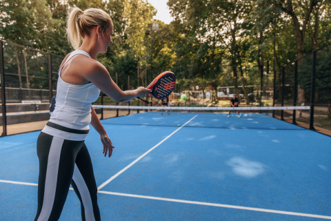Donna che gioca a padel su un campo blu all'aperto al Holiday Park «Kijkduin 1» nei Paesi Bassi.