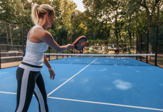 Frau spielt Padel-Tennis auf einem blauen Außenplatz im Holiday Park «Kijkduin 1» in den Niederlanden.
