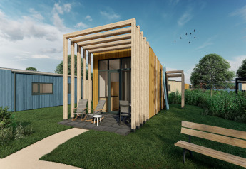 Modern tiny house with wooden facade and pergola at Holiday Park Klein Vink 23, set in green surroundings.