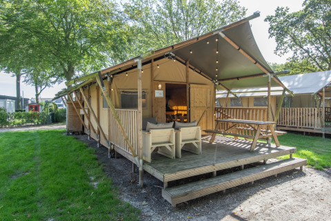 Tenda safari presso Holiday Park Klein Vink 20 con terrazza in legno, posti a sedere e area verde.