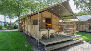 Safari-telt ved Holiday Park Klein Vink 20 med træterrasse, udendørs siddepladser og grønne omgivelser.