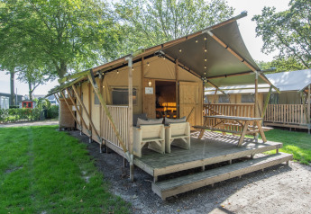 Tienda safari en Holiday Park Klein Vink 20 con terraza de madera, asientos exteriores y ambiente verde.