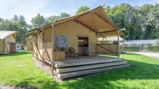 Safari-Zelt im Holiday Park Klein Vink 19 mit Holzterrasse und Sitzbereich in grüner, natürlicher Umgebung.