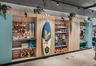 Shop display with Koos mascot items, surfboard, and plush toys at Holiday Park Kijkduin 1 in the Netherlands.
