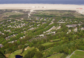 Aerial view of Holiday Park Kijkduin 1 in the Netherlands, showing green lodges, beach and sea beyond.