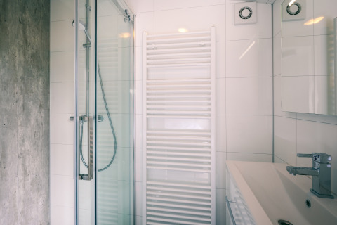 Modern lodge bathroom with a glass shower, white towel radiator, wall tiles, and contemporary sink.
