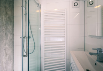 Modern lodge bathroom with a glass shower, white towel radiator, wall tiles, and contemporary sink.