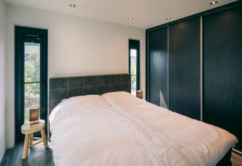 Modern bedroom at Holiday Park Zeedijk 2 in the Netherlands with a double bed and large black closets.