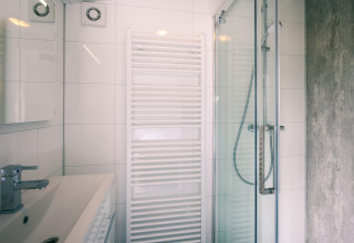 Modern bathroom with glass shower, sink, and towel radiator at Holiday Park Zeedijk 2 in the Netherlands.