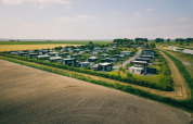 Aerial view of modern lodges surrounded by fields and nature, located in a peaceful rural landscape.