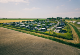 Luftaufnahme moderner Lodges inmitten grüner Felder und Natur, gelegen in einer ruhigen Landschaft.