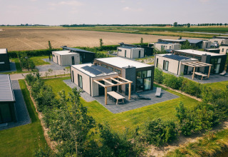 Vue aérienne du Holiday Park Zeedijk 2 aux Pays-Bas avec chalets modernes, pelouses et champs agricoles.