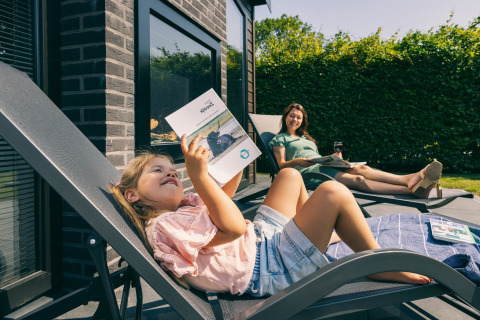 Madre e figlia si rilassano su lettini fuori da un lodge all'Holiday Park Zeedijk 2 nei Paesi Bassi.