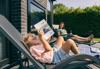 Mother and daughter relaxing on sun loungers outside a lodge at Holiday Park Zeedijk 2 in the Netherlands.