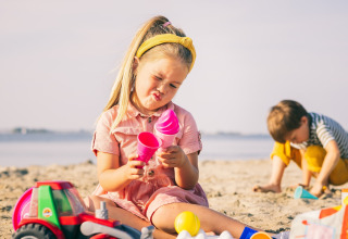 Deux enfants jouent avec des jouets de plage colorés sur le sable au Holiday Park « Zeedijk 2 » aux Pays-Bas.