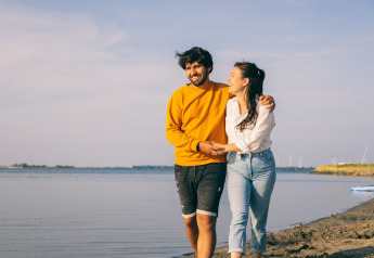 A happy couple walks by the water at Holiday Park «Zeedijk 2» in the Netherlands on a sunny day.