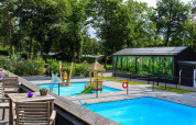 Hébergement de glamping avec piscines extérieures, aire de jeux pour enfants et arbres verdoyants sous le soleil.