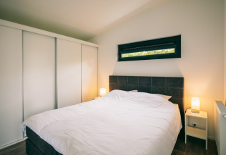 Dormitorio moderno con cama doble, mesitas de noche y armario en Holiday Park «Zeedijk 1» en Países Bajos.