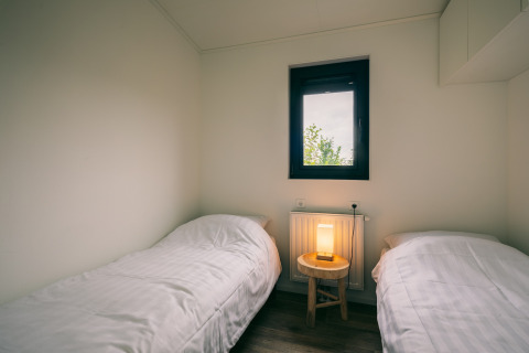 Dos camas individuales con ropa de cama blanca en una habitación minimalista del Holiday Park Zeedijk 1, Países Bajos.