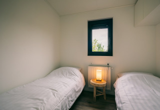 Due letti singoli con biancheria bianca in una stanza minimalista al Holiday Park Zeedijk 1, Paesi Bassi.