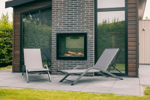 Patio esterno con due lettini e camino presso Holiday Park Zeedijk 1 nei Paesi Bassi, arredamento moderno.
