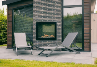Patio esterno con due lettini e camino presso Holiday Park Zeedijk 1 nei Paesi Bassi, arredamento moderno.